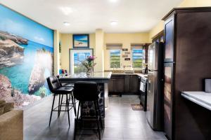 a kitchen with a bar with stools and a refrigerator at Elleamau in Island Harbour