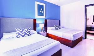 a bedroom with two beds and a blue wall at Apartment Tendenza Centro in Playa del Carmen