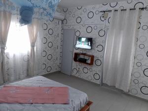um quarto com uma cama e uma televisão na parede em Partners Residence em Douala