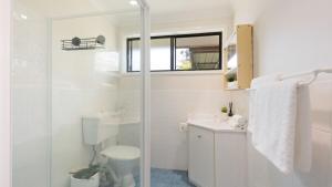 a white bathroom with a toilet and a shower at Sunrise Sands in Callala Beach