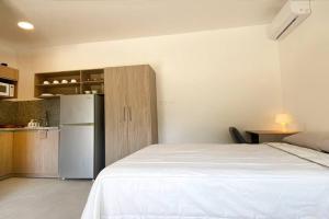 Schlafzimmer mit einem weißen Bett und einem Kühlschrank in der Unterkunft Estudio 1, Las Castañas in Santa Elena