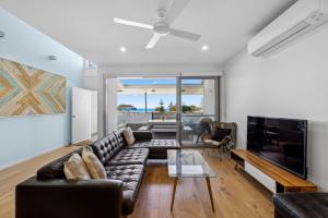 a living room with a couch and a tv at Woolgoolga Executive Apartment in Woolgoolga