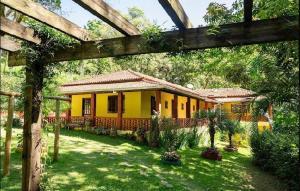 a yellow house in the yard of a house at Chácara Recanto do Berzelai in Bueno Brandão