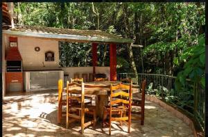 a wooden table and chairs on a patio at Chácara Recanto do Berzelai in Bueno Brandão