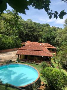 una casa con techo de baldosa y piscina en Chácara Recanto do Berzelai en Bueno Brandão
