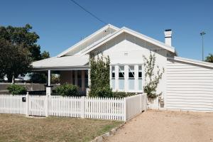 ein weißes Haus mit einem weißen Gartenzaun in der Unterkunft Lexton House - Luxurious Cottage in Parkes