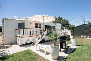 ein weißes Haus mit Sonnenschirm und Grill in der Unterkunft Lexton House - Luxurious Cottage in Parkes
