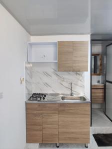 a kitchen with wooden cabinets and a sink at Apartahotel Sevilla in Medellín