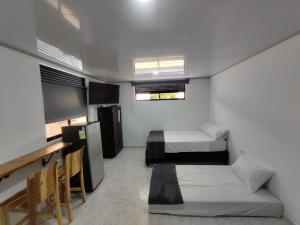 Habitación pequeña con 2 camas y escritorio. en Apartahotel Sevilla en Medellín