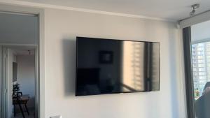 uma televisão de ecrã plano numa parede numa sala de estar em Hermoso y comodo Departamento con vista al mar, costas de montemar em Concón