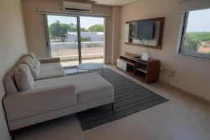 uma sala de estar com um sofá e uma TV em Edificio Carmelitas insuperable una habitación em Assunção