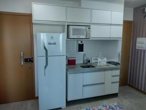 uma cozinha com armários brancos e um frigorífico em Excelente apartamento 02 quartos frente ao mar em Salvador
