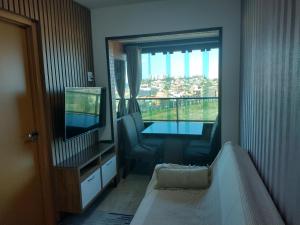 um quarto com uma televisão, uma mesa e uma janela em Excelente apartamento 02 quartos frente ao mar em Salvador