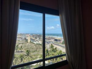 een raam met uitzicht op het strand en de oceaan bij Excelente apartamento 02 quartos frente ao mar in Salvador
