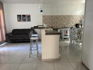 a kitchen and living room with a counter and stools at Casa Cantinho da Família - Praia de Guaibim - in Guaibim