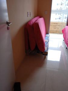 une chambre avec un canapé rose dans l'angle d'une pièce dans l'établissement Apartamento novo Vila Guilhermina, à Praia Grande