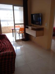 un salon avec une télévision et une table avec une télévision dans l'établissement Apartamento novo Vila Guilhermina, à Praia Grande
