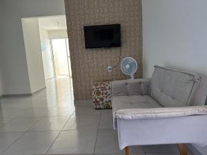 uma sala de estar com um sofá e uma televisão de ecrã plano em Casa Cantinho da Família - Praia de Guaibim - em Guaibim