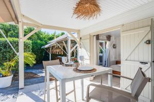 a patio with a white table and chairs on a porch at Magnifique Bungalow et Jacuzzi au cœur des plages in Le Moule