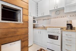 a kitchen with white cabinets and a stove at Morada da Montanha 2 dorm by Achei Gramado in Gramado