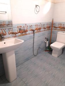 uma casa de banho com um lavatório e um WC e uma parede com flamingos em Green Village em Ella