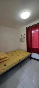 Cette petite chambre comprend un lit et un rideau rouge. dans l'établissement 3-Bedroom House, à Butuan