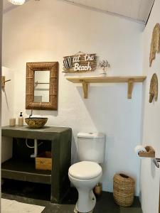 a bathroom with a toilet and a mirror and a sink at Casa Serena - Na praça, ao lado da Igrejinha in Caraíva