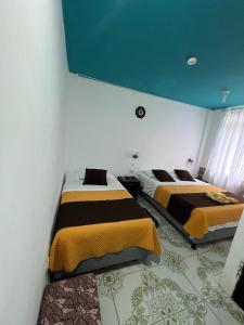 two beds in a bedroom with a blue ceiling at Hostal Brisas Del Mar in Puerto Villamil