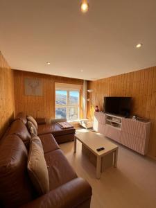 ein Wohnzimmer mit einem braunen Ledersofa und einem Tisch in der Unterkunft DÚPLEX CON VISTAS ZONA MEDIA in Sierra Nevada