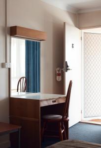 a desk in a room with a window and a chair at Holiday Lodge Motor Inn in Narooma