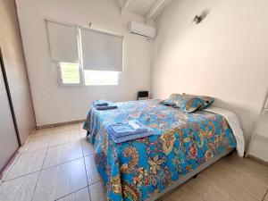 1 dormitorio con 1 cama con manta azul y ventana en Calle Republica de Italia en Neuquén
