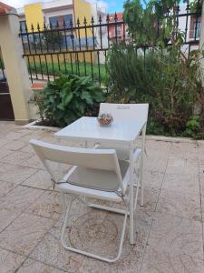 una mesa blanca y una silla con un tazón. en Hospedagem Emanuel en Caneças