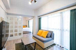 - un salon avec un canapé et un oreiller jaune dans l'établissement REBANGA Juso Apartment, à Osaka