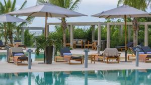 a pool with lounge chairs and umbrellas next to the water at Cartagena, Morros Zoe apto acceso directo a playa in Cartagena de Indias