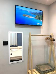 uma televisão de ecrã plano pendurada numa parede com um espelho em valenshostel em Angra dos Reis