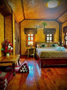 a bedroom with a large bed and a table at เรือนร่มไม้รีสอร์ท RuenRomMai Resort in Ban Klang Mun