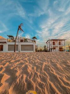 a person standing in the sand in front of a house at Chalé Galo Preto in Galinhos