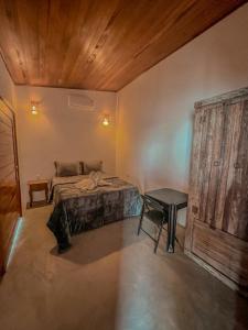 a bedroom with a bed and a table and a wooden ceiling at Chalé Galo Preto in Galinhos