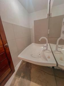 a white bathroom with a sink and a mirror at Chalé Galo Preto in Galinhos