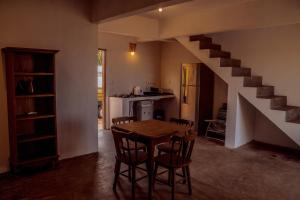 a kitchen and dining room with a table and a staircase at Chalé Galo Preto in Galinhos