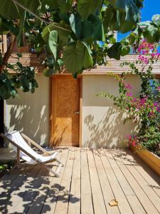 a chair sitting on a wooden porch with flowers at Alma Loft in Máncora