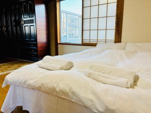 Una cama blanca con toallas y una ventana. en Snow Fever - Clan en Hakuba