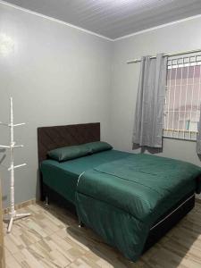 um quarto com uma cama com lençóis verdes e uma janela em Casa de praia em Penha em Penha