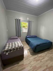 two beds sitting in a room with a window at Casa de praia em Penha in Penha