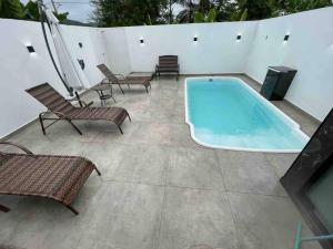 uma piscina num pátio com cadeiras e uma televisão em Casa de praia em Penha em Penha