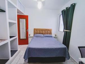 1 dormitorio con 1 cama y puerta roja en Apartamento Vista Linda - com suíte - Bertioga - Prox ao SESC, Riviera, Indaiá, en Bertioga