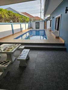 a swimming pool with two benches and a table at Pool Villa Baan Sanook Cha-am in Cha Am