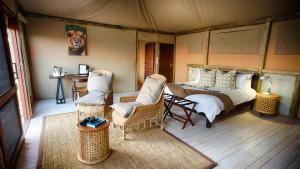 ein Schlafzimmer mit einem Bett und Stühlen in einem Zelt in der Unterkunft Ghoha Hills Savuti Lodge in Savuti