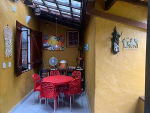 uma sala de jantar com uma mesa vermelha e cadeiras vermelhas em Chalé Praia de Boiçucanga em Boicucanga