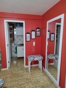 een rode keuken met 2 krukken en een spiegel bij Apartamento Caiobá Pé na areia. Quadra do Mar. in Matinhos